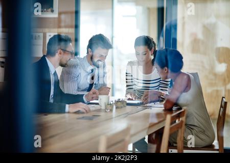 Prendre leurs idées en ligne. Par la photo d'un groupe de collègues travaillant ensemble dans un bureau. Banque D'Images