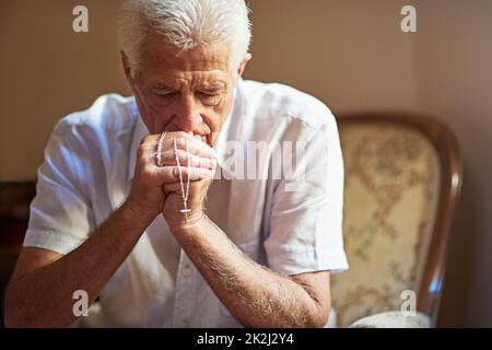 Combattre la peur avec la foi. Plan court un homme âgé tenant un rosaire dans la prière. Banque D'Images