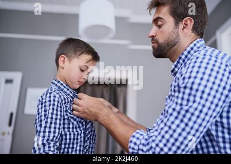 Laissez-moi vous aider avec ce bouton. Coupe courte d'un beau jeune homme et de son fils qui s'habille le matin. Banque D'Images