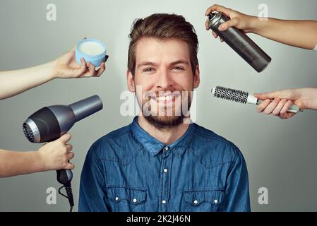 Mélangez votre look avec un relooking. Studio portrait d'un jeune homme qui se fait un relooking de cheveux sur un fond gris. Banque D'Images