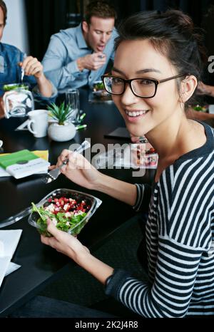 Mettre leurs esprits créatifs au travail. Portrait d'un jeune employé de bureau mangeant un déjeuner avec ses collègues à une table de réunion. Banque D'Images