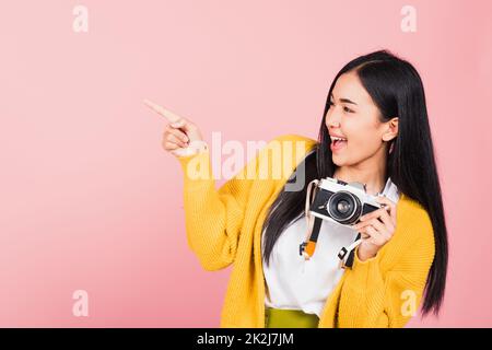 femme adolescente souriante tenant un appareil photo d'époque et un doigt pointé Banque D'Images