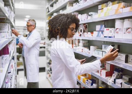 Plus les mains sont nombreuses, moins le travail est important. Photo de deux pharmaciens spécialisés qui se promo et qui font du stock à l'intérieur d'une pharmacie. Banque D'Images