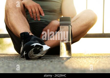 Jogger assis sur la route après son entraînement à l'extérieur Banque D'Images
