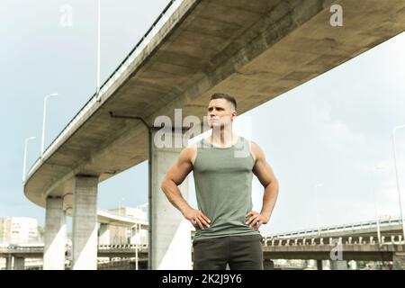 Jeune homme sportif portant des vêtements de sport kaki après son entraînement dans la rue Banque D'Images
