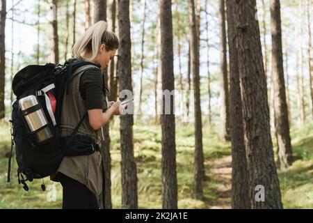 Une femme de randonnée utilise un smartphone pour la navigation dans la forêt verte Banque D'Images