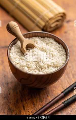 Riz au risotto carnaroli non cuit dans un bol et une cuillère en bois. Banque D'Images