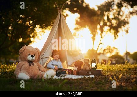 Tout ce dont il a besoin, c'est d'un peu d'imagination. Portrait d'un petit garçon mignon jouant dans son tipi à l'extérieur. Banque D'Images