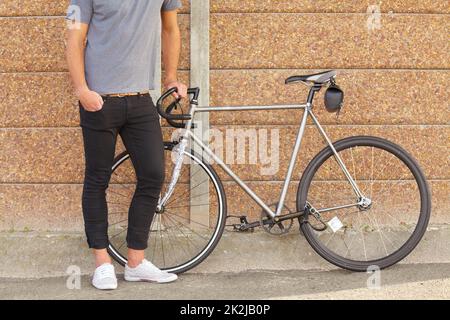 Transport écologique. Un petit cliché d'un jeune homme debout à côté d'un vélo. Banque D'Images