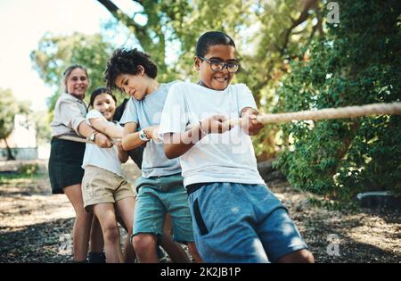 Ont tous gagné quand ont joué ensemble. Prise de vue d'un groupe d'adolescents jouant un jeu de remorqueurs de guerre au camp d'été. Banque D'Images