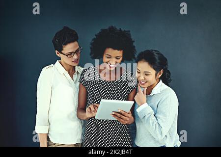 Jetez un coup d'œil à Photo d'une jeune femme d'affaires montrant quelque chose à ses collègues sur une tablette dans le studio. Banque D'Images