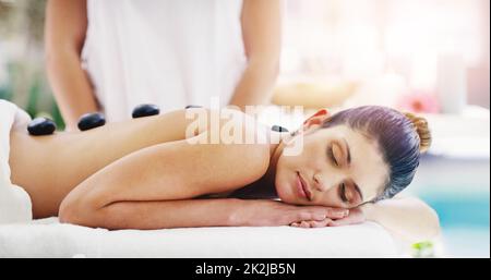 Ces pierres vont éliminer toute votre tension. Photo d'une jeune femme recevant un massage aux pierres chaudes dans un spa. Banque D'Images