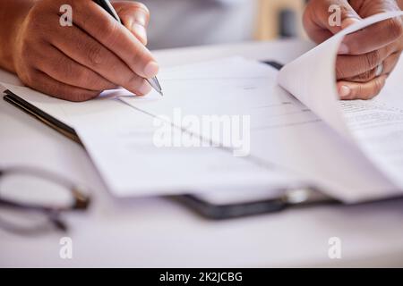 Remplir quelques documents. Photo courte d'un homme d'affaires méconnu qui remplit ses papiers pendant qu'il est assis dans son bureau. Banque D'Images