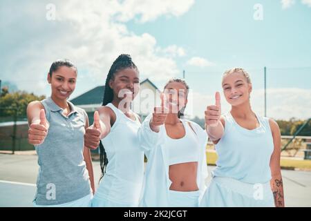 Étaient prêts pour le défi. Photo d'un groupe diversifié de femmes se tenant ensemble sur un court de tennis et montrant un pouce vers le haut. Banque D'Images