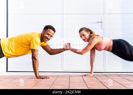 Entraînement de couple sportif interracial à l'extérieur - couple multiracial portant des vêtements de sport et faisant de l'entraînement fonctionnel à l'extérieur pour les muscles tendus du corps, Banque D'Images