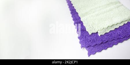 Tissu en microfibre violet et vert clair, mis en évidence sur un fond blanc. Nouveau matériau en microfibre douce pour le nettoyage des objets et des surfaces. Bannière avec une copie de l'espace Banque D'Images