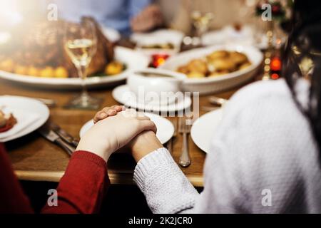 Rien ne réunit la famille comme le déjeuner de Noël. Photo courte de personnes méconnues tenant les mains dans la prière avant de déjeuner de Noël ensemble. Banque D'Images