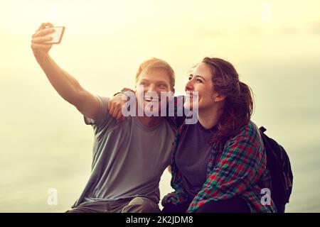 C'est le jour qu'il a proposé. Photo courte d'un jeune couple prenant un selfie sur un sommet de montagne. Banque D'Images