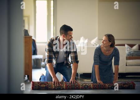 Envoyez des messages instantanés ici pour vous aider avec tout ce dont vous avez besoin. Photo d'un jeune couple marié roulant sur un tapis ensemble à la maison. Banque D'Images