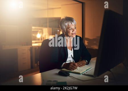 Si ça vaut le coup, travaillez pour ça. Photo d'une femme d'affaires mûre écrivant dans un ordinateur portable et utilisant un ordinateur pendant une nuit de travail. Banque D'Images