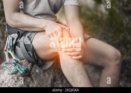 Genou, blessure et douleur avec un homme assis sur un rocher pour faire une pause pendant la randonnée, le rocher ou l'escalade de montagne dans la nature. CGI d'inconfort de la crampes Banque D'Images