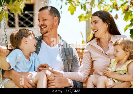 Donnez-leur une enfance à sourire. Photo d'une famille de quatre personnes se détendant ensemble sur une balançoire de jardin. Banque D'Images