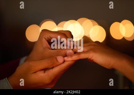 Il l'aimait donc il y a mis un anneau. Gros plan d'un homme mettant une bague d'engagement sur son doigt de fiancé. Banque D'Images