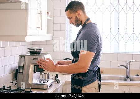 L'heure du café est la meilleure heure de la journée. Prise de vue d'un jeune homme utilisant une machine à café pour se préparer une boisson. Banque D'Images