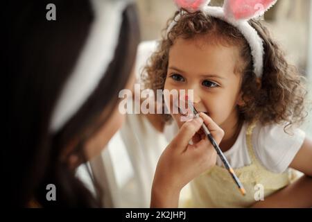 Bon séjour pour moi. Photo d'une femme peignant le visage de ses filles pendant les vacances de pâques. Banque D'Images