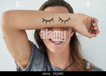 Souriant pour correspondre à ces yeux. Coupe courte d'un jeune homme méconnaissable levant le bras devant les yeux. Banque D'Images