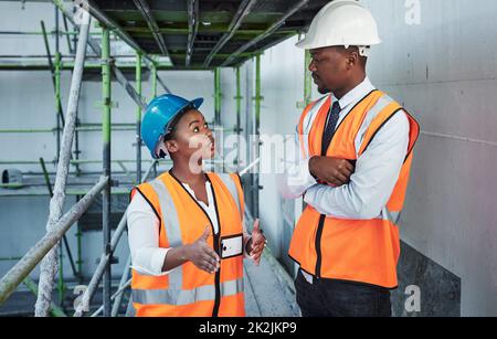 Les compétences combinées sont les éléments de base de la réussite. Photo d'un jeune homme et d'une jeune femme ayant une discussion pendant qu'ils travaillent sur un chantier de construction. Banque D'Images