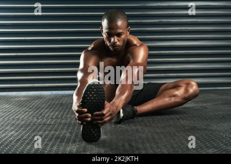 Se réchauffer pour son entraînement. Prise de vue en longueur d'un jeune sportif qui passe par sa routine d'échauffement en studio. Banque D'Images