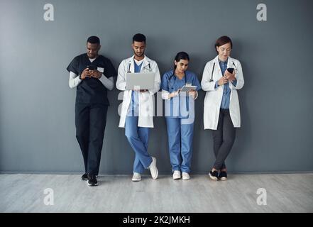 C'est en fait notre pause déjeuner. Cliché d'un groupe de médecins debout sur fond gris au travail. Banque D'Images