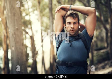 Je m'étire toujours avant de m'étirer. Portrait court d'un beau jeune homme qui s'étire avant de partir pour sa randonnée dans les montagnes. Banque D'Images