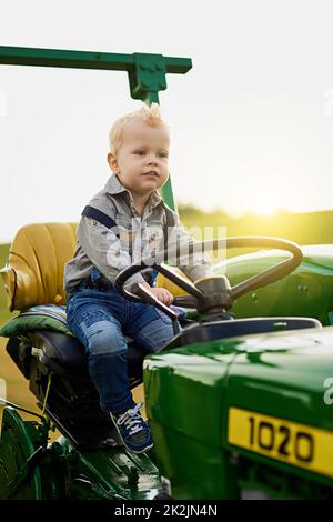 Le fermier le plus subtil. Photo d'un adorable petit garçon à bord d'un tracteur sur une ferme. Banque D'Images