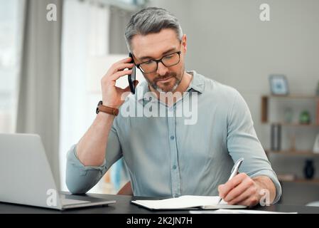 Au téléphone avec son banquier privé. Plan court d'un beau homme mûr faisant un faux-faux tout en travaillant sur ses finances à un bureau à la maison. Banque D'Images