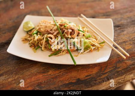 Profitez de votre repas. Gros plan de la nourriture chinoise sur une assiette sur une table en bois. Banque D'Images