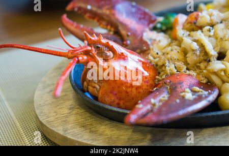 Steak de homard de style japonais servi sur une poêle chaude avec des légumes beurrés comme accompagnement. Banque D'Images