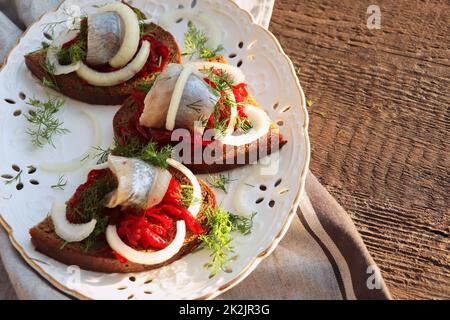 Filet de hareng.Cuisine scandinave. Sandwich avec des tranches de filet de hareng mariné de l'Atlantique, salade de betteraves, oignon et micro-vert. Banque D'Images