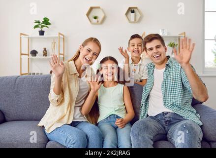 Les jeunes familles avec deux enfants brandir les mains devant la webcam pour accueillir leurs proches. Banque D'Images