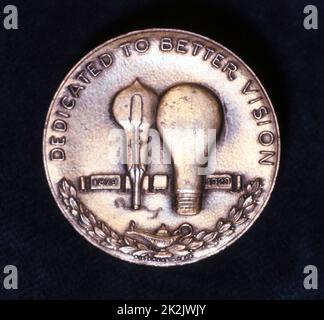 Thomas Alva Edison (1847-1931) physicien et inventeur américain. Inverse d'une médaille célébrant le 50th anniversaire de son invention de la lampe à incandescence. Le globe de gauche est la première lampe à filament de carbone utilisable d'Edison utilisant du bambou carbonisé Banque D'Images