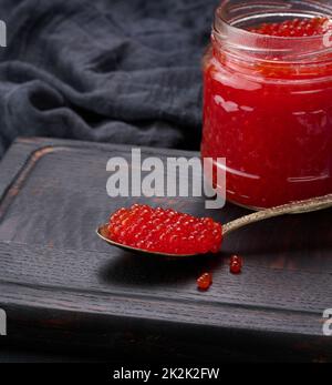 caviar rouge granuleux frais dans un pot en verre sur une table en bois Banque D'Images