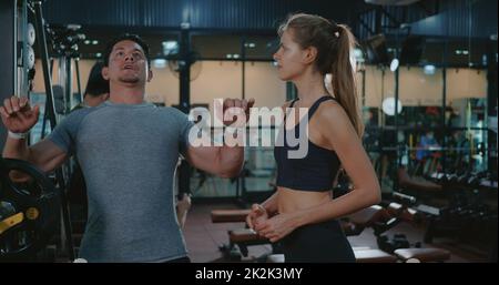 Entraîneur de fitness parlant expliquant la musculation de banc d'entraînement avec le programme de barbell à la femme cliente Banque D'Images