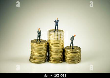 Hommes d'affaires sur pile de pièces. Concept de concurrence d'entreprise Banque D'Images