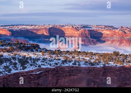 Washer Woman Arch & the Monster Tower above the clouds of a winter temperature inversion in Canyonlands National Park, Moab, Utah.  Viewed from Buck C Stock Photo