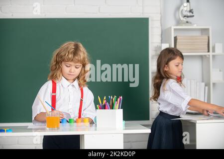 Portrait des enfants de l'école faisant des devoirs d'art. Les enfants qui s'en vont à l'école primaire. Joli dessin enfant avec crayons colorés. Banque D'Images