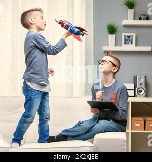 Mignon jeune garçon jouant avec un jouet fusée sur un canapé Banque D'Images