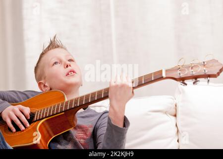 petit garçon jouant de la guitare à la maison Banque D'Images