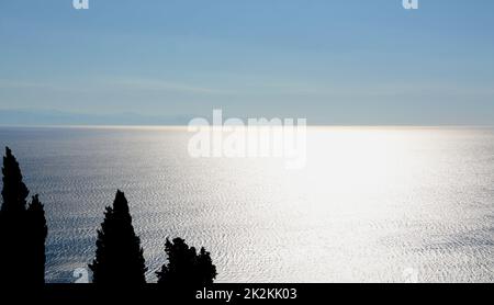 Silhouettes de cyprès devant les réflexions infinies de la mer Ligurienne. Banque D'Images