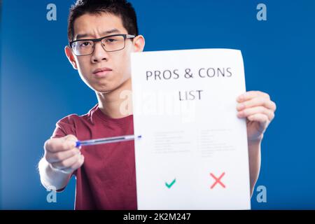 inquiet asiatique gars montrant une liste pour et contre Banque D'Images